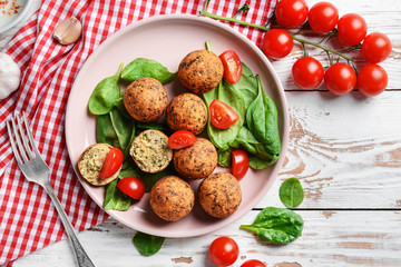 Plate with tasty falafel balls on wooden table