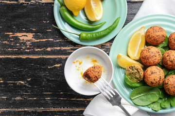 Tasty falafel balls with sauce on wooden table
