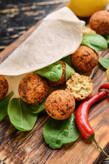 Tasty falafel balls with flatbread and spinach on wooden board