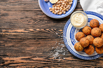 Plate with tasty falafel balls and sauce on wooden table