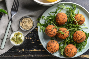 Plate with tasty falafel balls on wooden table