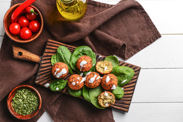 Board with tasty falafel balls and spinach on table