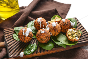Tasty falafel balls and spinach on wooden board