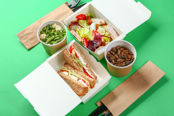 Containers with delicious food on color background