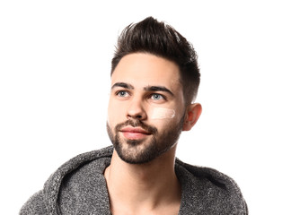 Handsome man with cosmetic clay on his face against white background