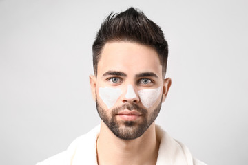Fototapeta premium Handsome man with cosmetic clay on his face against light background