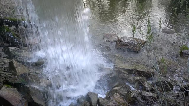 Water in a waterfall falls on stones close up