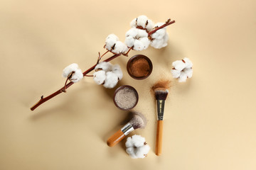 Cosmetic clays in bowls with brushes on color background