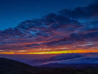 sunrise at Doi Inthanon, mountain view misty morning of the hills around with sea of fog with red sun light and cloudy sky background, KM.41 local of Doi Inthanon National Park, Chiang Mai, Thailand.