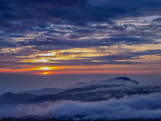 sunrise at Doi Inthanon, mountain view misty morning of the hills around with sea of fog with red sun light and cloudy sky background, KM.41 local of Doi Inthanon National Park, Chiang Mai, Thailand.
