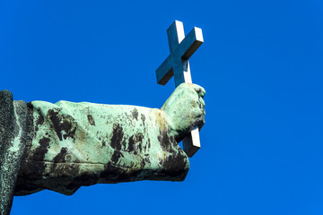 Holy Christian cross in copper rust covered hand isolated on blue sky background - concept Christianity Catholicism religion Christ god church forgiveness exorcism belief faith strength prayer worship