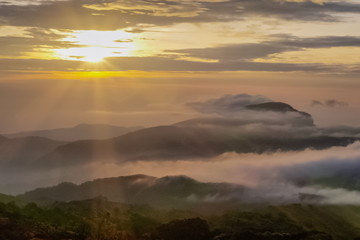 sunrise at Doi Inthanon, mountain view morning of the hills around with sea of fog with sun rays and yellow sky background, KM.41 View Point, Doi Inthanon, Chiang Mai, Thailand.