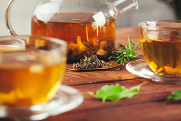 glass teapot with cup of black tea on wooden table