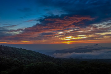 Obraz premium sunrise at Doi Inthanon, mountain view misty morning of the hills around with sea of fog with red sun light and cloudy sky background, KM.41 local of Doi Inthanon National Park, Chiang Mai, Thailand.