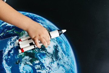 The child's hand plays with the spaceship.