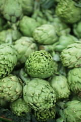 Close up of bunch of green artichokes at the organic supermarket vegetables department. Sustainable agriculture.
