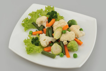 Different green vegetables on the plate gray background