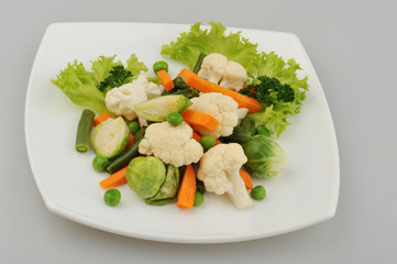 Different green vegetables on the plate gray background
