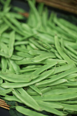 Bunch of organic grown fresh green pea pods on a supermarket shelves and busckets. Healthy eating habits. Diet ideas. Spring and summer veggies. Vegetables. Shot in Barcelona, Spain. 