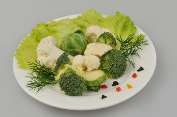 Different green vegetables on the plate gray background