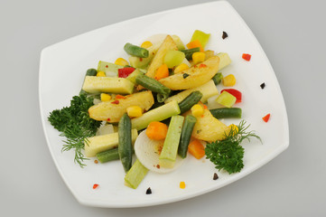 Different green vegetables on the plate gray background