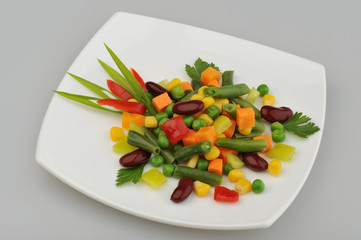 Different green vegetables on the plate gray background