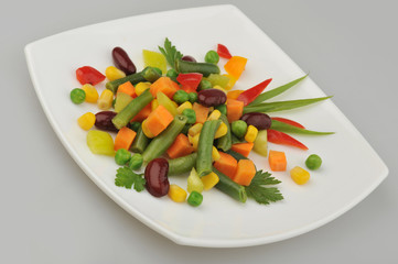 Different green vegetables on the plate gray background
