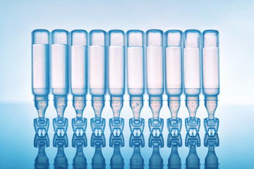 Tears eye drops in plastic pipettes blue background upside down