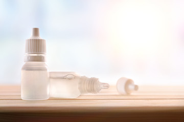 Plastic bottle with eye medication on wooden table in room