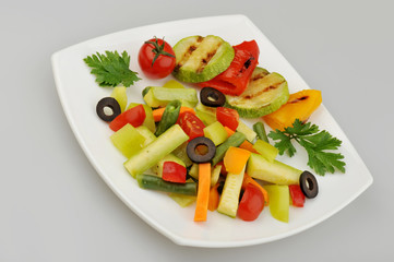 Different green vegetables on the plate gray background