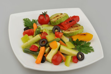 Different green vegetables on the plate gray background