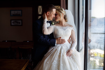 Naklejka premium portrait of emotional lovers of brides indoor.Bride and groom kisses tenderly . emotional photo of a couple in love on the wedding day.smiling newlyweds. Wedding photography. 