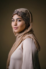 Studio portrait of a beautiful, young and attractive Muslim Middle Eastern woman in a brown hijab...