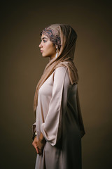 Portrait head shot of a young and beautiful Muslim woman (Indonesian in a brown traditional outfit...