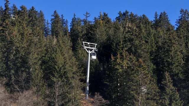 Time lapse of a bubble ski lift passing through a gap in a forest in the French Alps