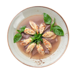 soup with slices of beef, and pancakes rolled into a roll, decorated with greens. isolated on white background
