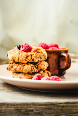 Oatmeal and apple cookies in bowl with berries and date caramel photographed with natural light (Selective Focus, Focus on the front of the cookie in the middle