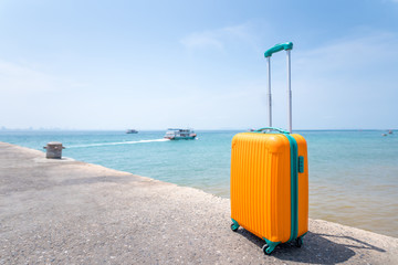 Big orange travel bag and the sea beautiful blue sky with boat background, Vacation concept.