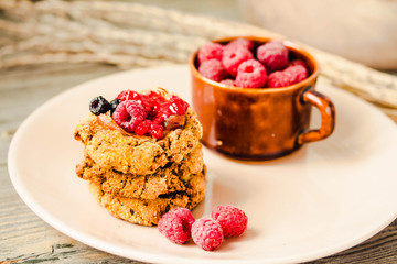 Homemade crunchy oatmeal cookies with raspberry jam and date caramel on a grey wooden background. Horizontal.
