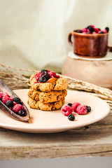 Fototapeta na wymiar Homemade vegan crunchy oatmeal cookies with raspberry jam and date caramel on a grey wooden background.