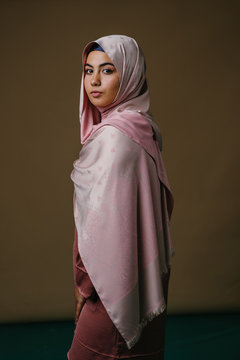 Studio portrait of a beautiful young Asian woman in a pink dress and hijab head scarf.