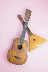 Old wooden musical instruments: guitar and balalaika on a pink background. Music concept