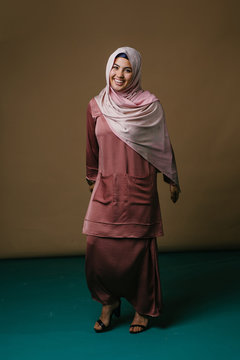 Studio portrait of a beautiful young woman in a pink shirt and a hijab head scarf.