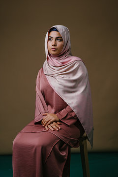 Studio portrait of a beautiful young woman in a pink shirt and a hijab head scarf.