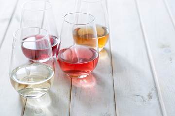 WIne tasting concept - red, rose, white and orange wine in glasses on wood background