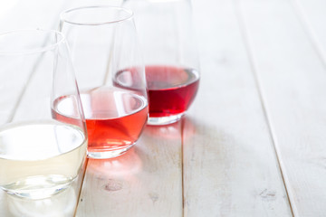 WIne tasting concept - red, rose and white wine in glasses on wood background