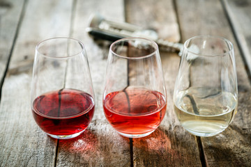 WIne tasting concept - red, rose and white wine in glasses on wood background