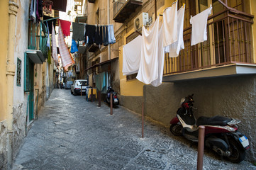 Fototapeta na wymiar Quiet view of classic narrow laundry-lined street of the historic medieval center of Naples, Italy