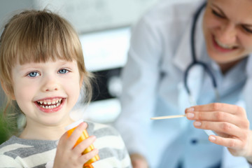 Cute smiling happy little girl hold in hand bottle of tablets at doctor office portrait