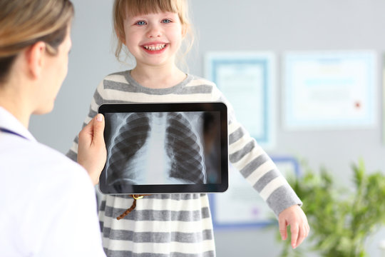 Female doctor examining little girl with ultra modern scanning tablet pc device closeup